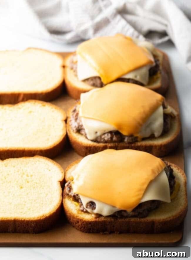 Texas toast slices topped with cooked burger patties, ready for the top bread layer.