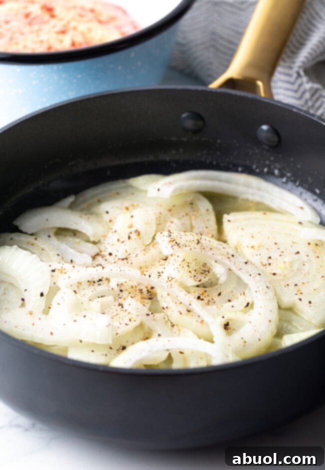 Raw onion slices in a skillet, beginning to cook.