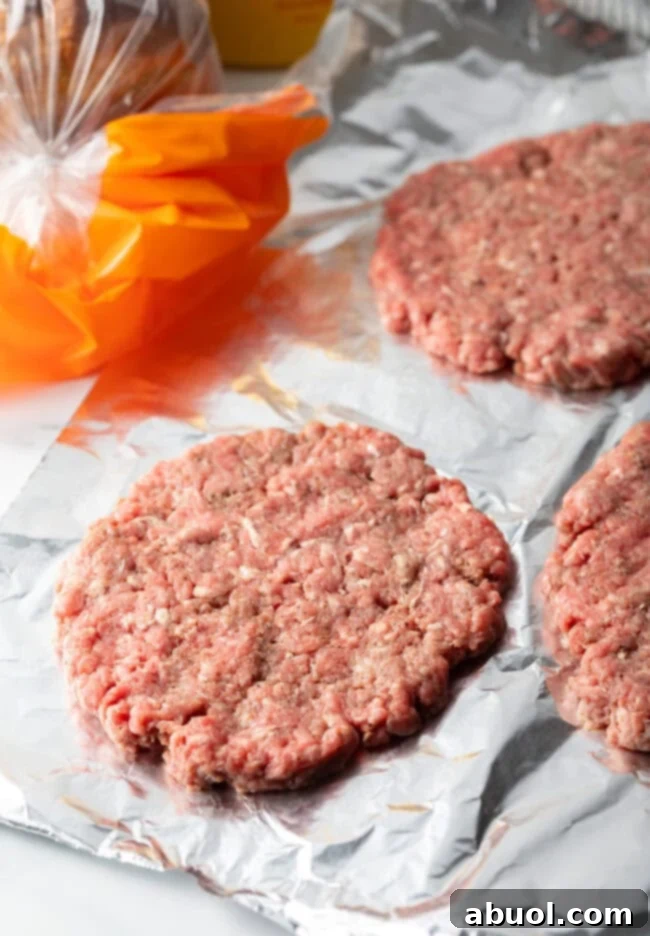 Raw burger patty shaped into an oval on parchment paper.
