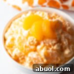 Top down view of mandarin orange fluff salad in a white bowl, garnished with 3 slices of oranges.