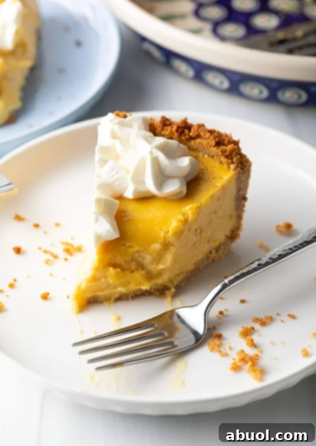 Slice of mango tart on a white plate, bite taken out of the tip and metal fork to the side.