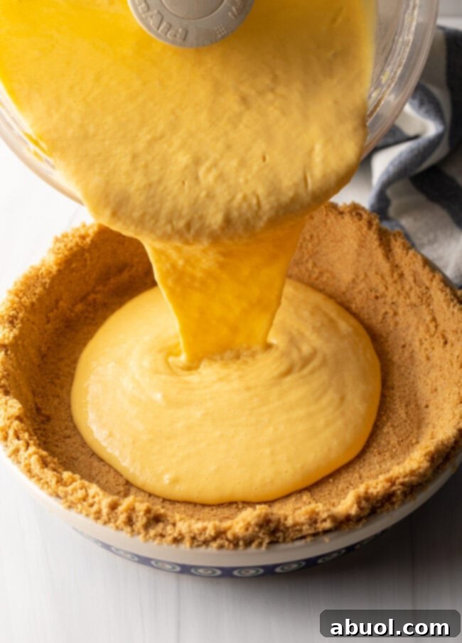 Pouring mango curd into the graham cracker pie crust.