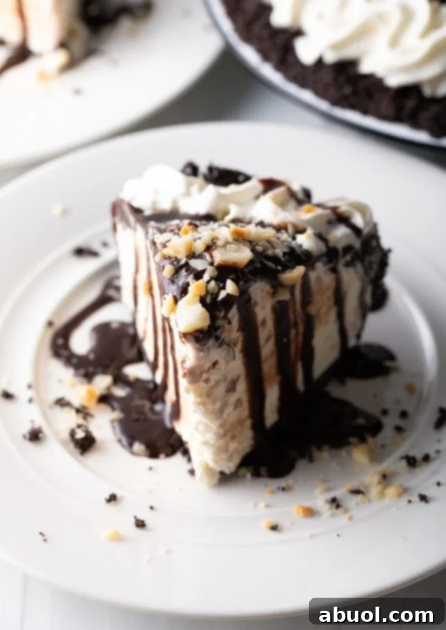 A generous slice of Duke's Hula Pie, showcasing layers of chocolate crust, macadamia nut ice cream, and fudge topping, served on a pristine white plate.