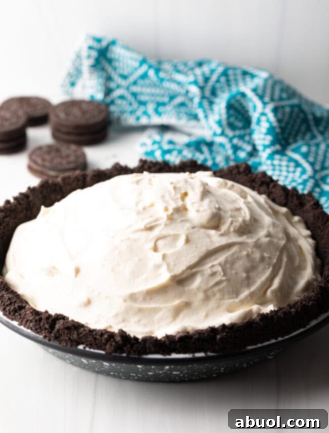 Creamy macadamia nut ice cream mixture smoothed evenly into the prepared Oreo cookie pie crust, ready for freezing.