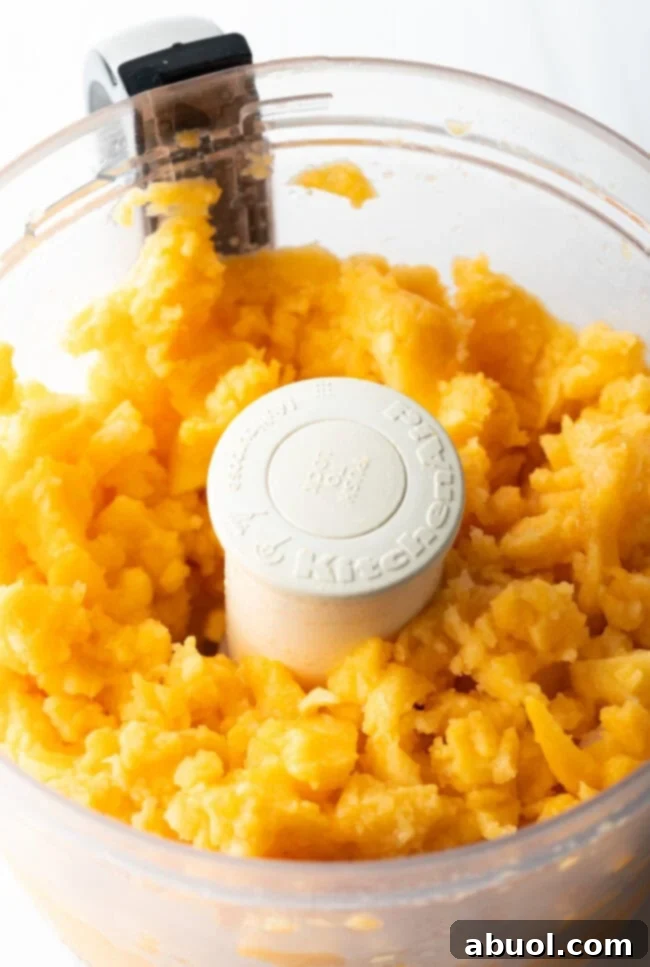 Close-up of fresh peaches being perfectly pureed in a food processor, achieving a smooth yet chunky texture ideal for preserves.