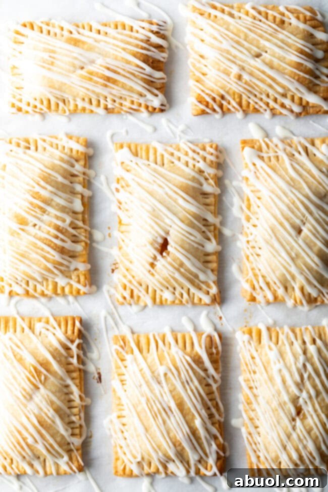 Homemade Peach Toaster Pastries 13 A top-down view of eight finished peach hand pies, each generously drizzled with a smooth white icing, creating an enticing pattern.