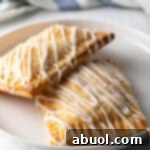 Two homemade peach pop tarts resting against each other on a white plate.