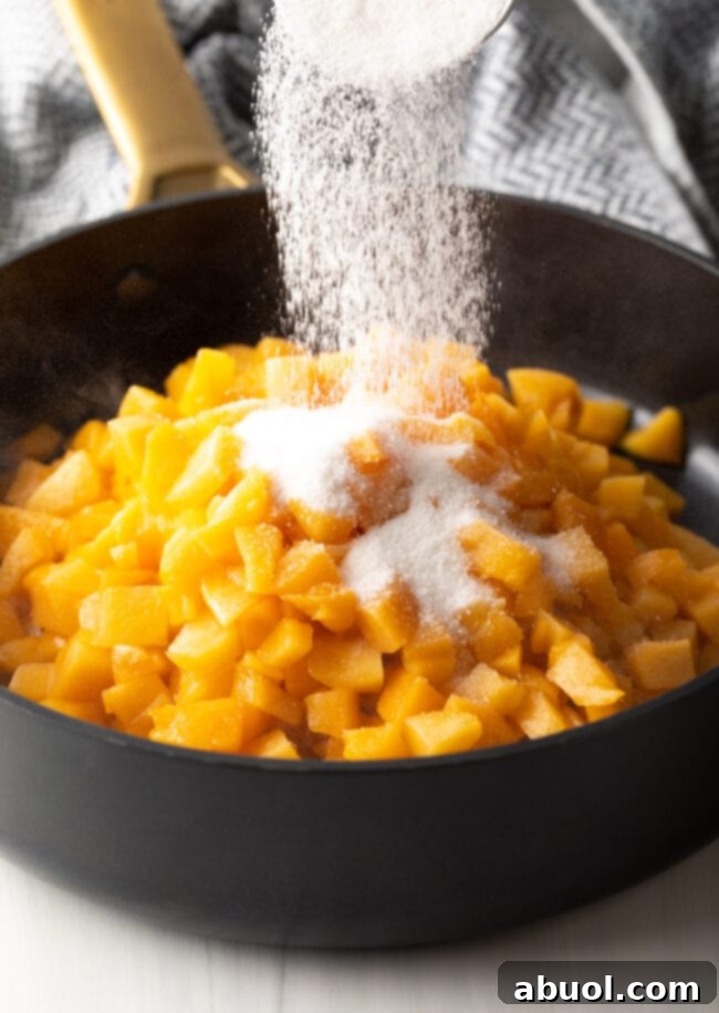 Homemade Peach Toaster Pastries 6 Freshly chopped peaches being combined with sugar in a large black pot on the stove, beginning the filling process.