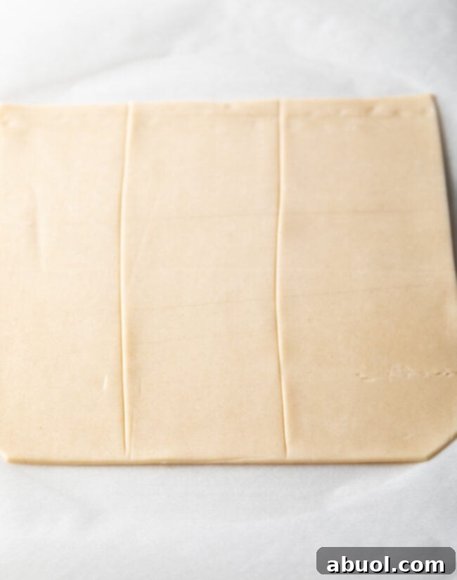 Homemade Peach Toaster Pastries 8 A rolled-out pie pastry sheet meticulously cut into three long, even sections, ready for filling.