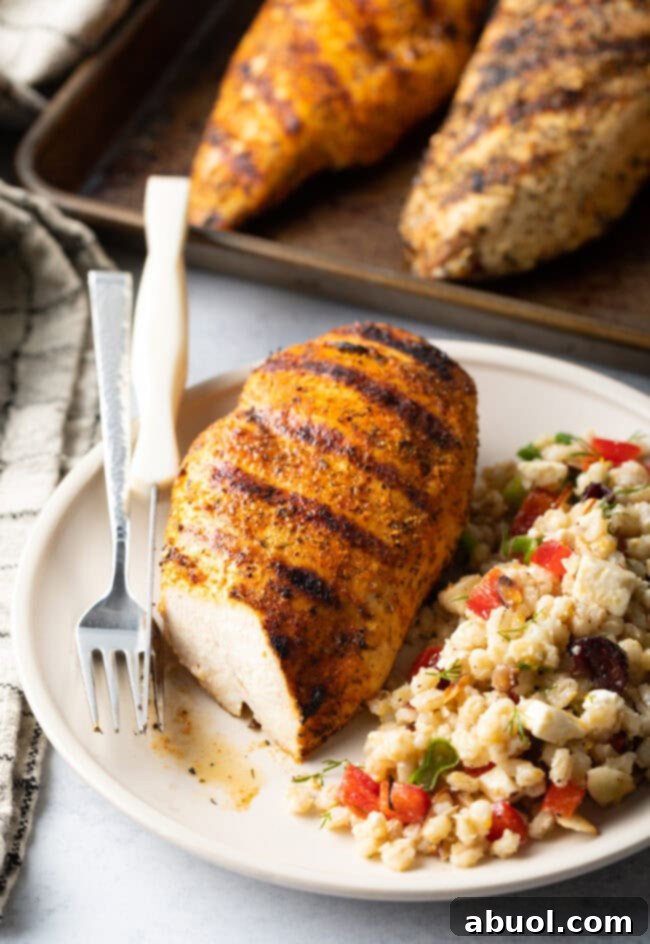 Seasoned grilled chicken breast sliced in half to show its juicy interior, served with a vibrant bean salad on a white plate.