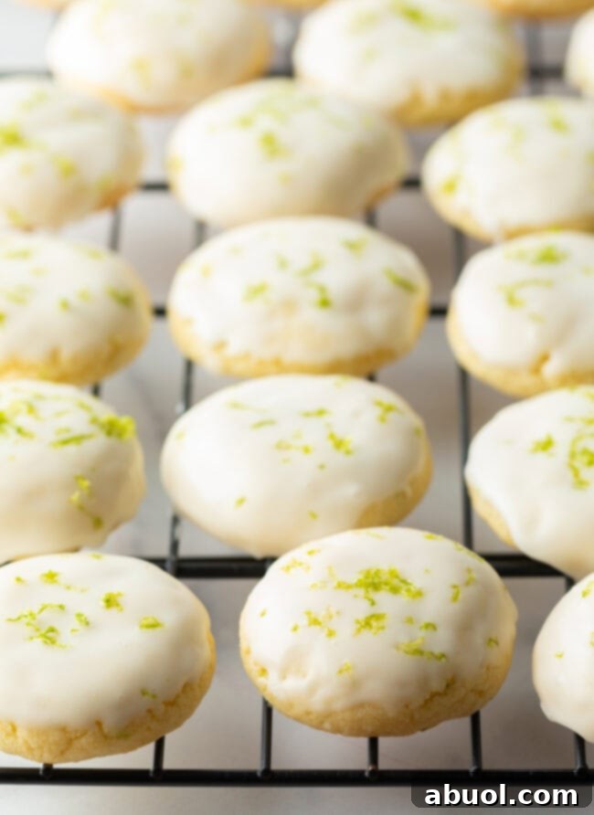 A wire cooling rack neatly arranged with several freshly glazed key lime cookies, allowing the glaze to set perfectly.