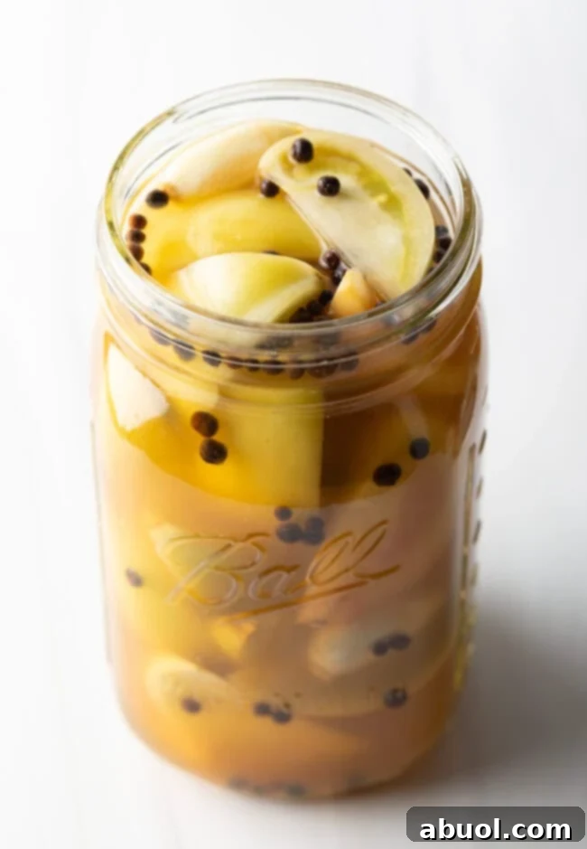 Marinated pickled green tomatoes in a large glass jar.