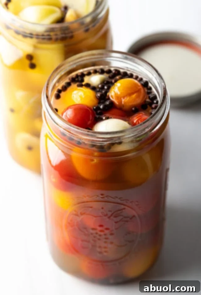 Marinated pickled cherry tomatoes in a large glass jar.