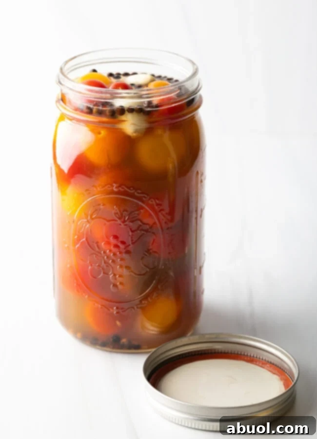 Marinated pickled cherry tomatoes in a large glass jar.