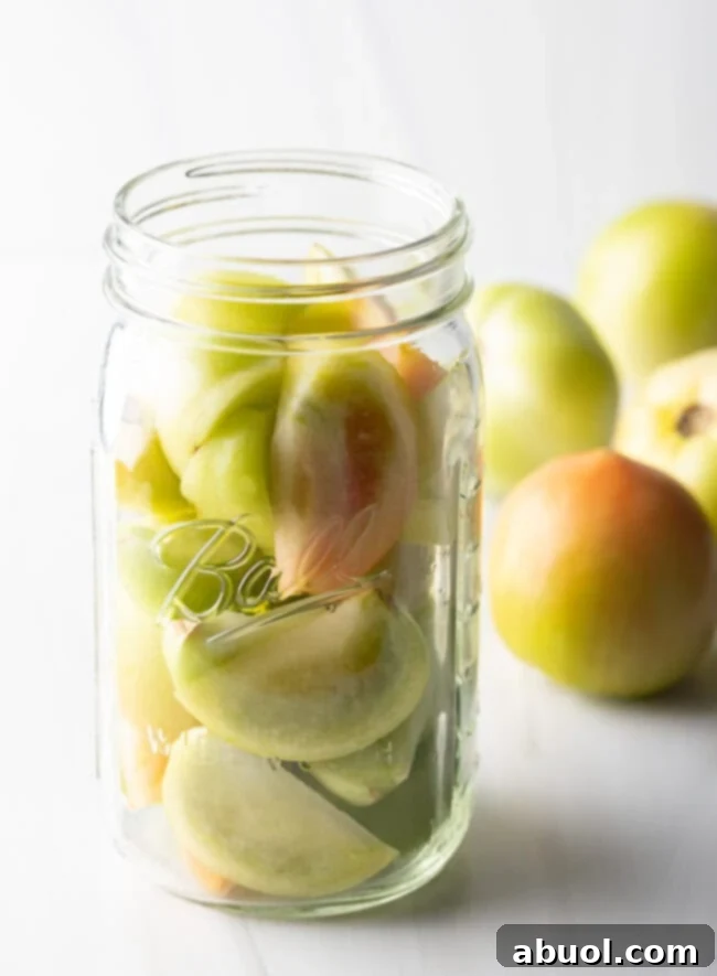 Small green tomatoes in a large glass ball jar.