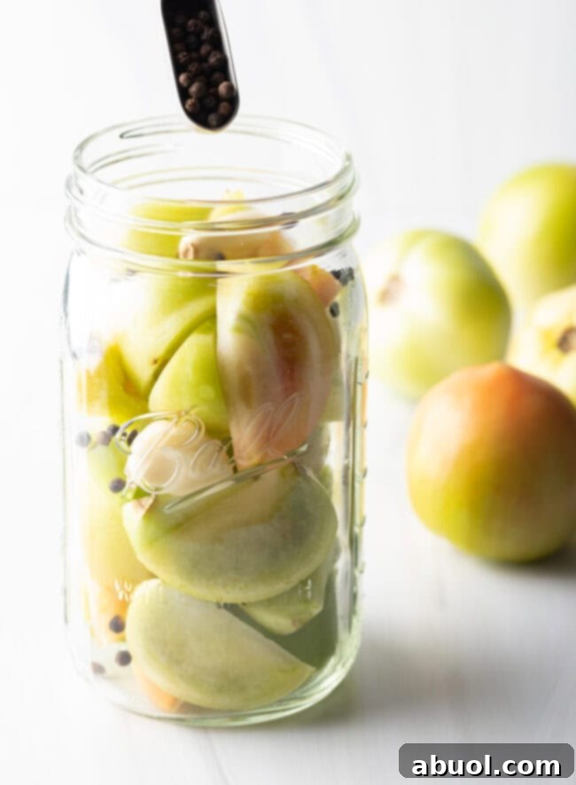 Small green tomatoes in a large glass ball jar.