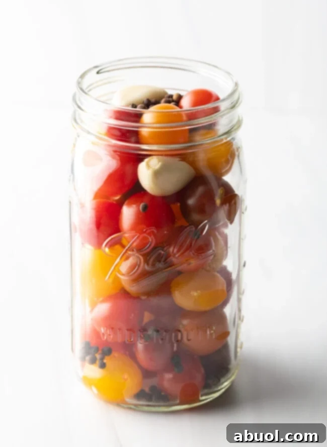 Small yellow and red cherry tomatoes in a large glass ball jar.