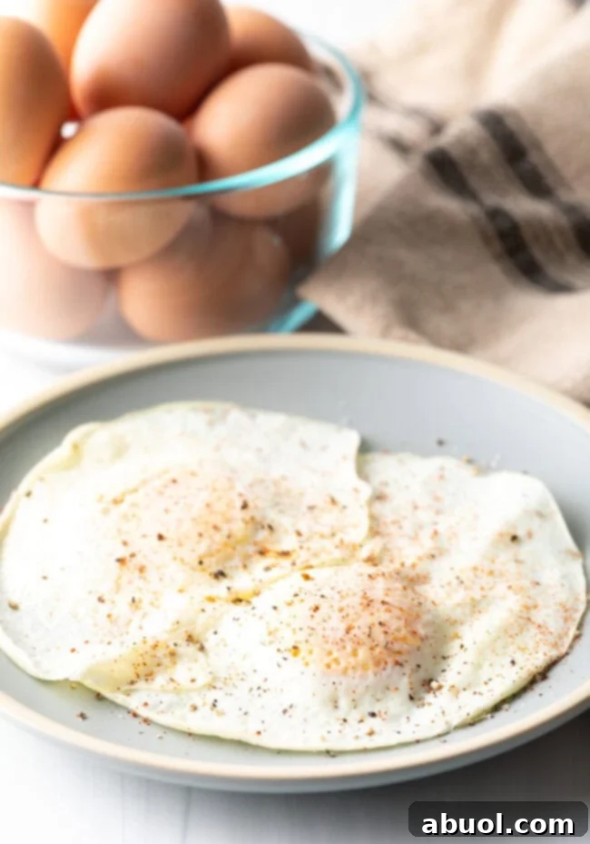 Two cooked eggs over easy on a light blue plate, sprinkled with spices.