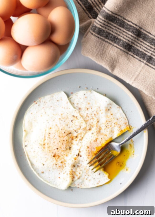 Fork cutting into th soft yolk of a gently over easy fried egg, on a light blue plate.