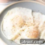 Two cooked eggs over easy on a light blue plate, sprinkled with spices.