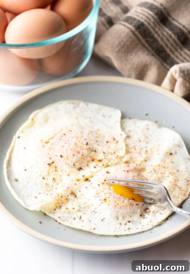 Fork cutting into th soft yolk of a gently over easy fried egg, on a light blue plate.