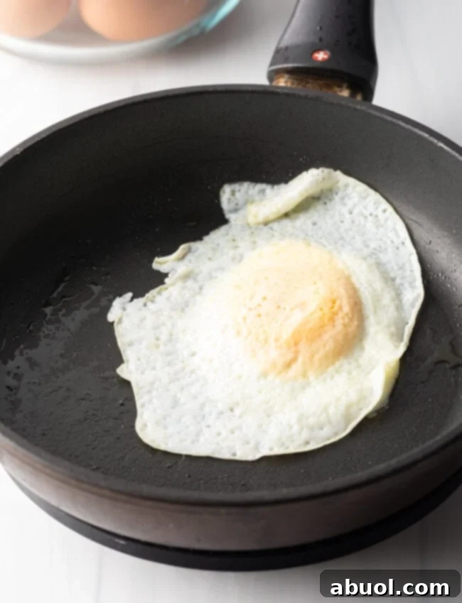 Soft fried egg over easy in a black nonstick skillet.