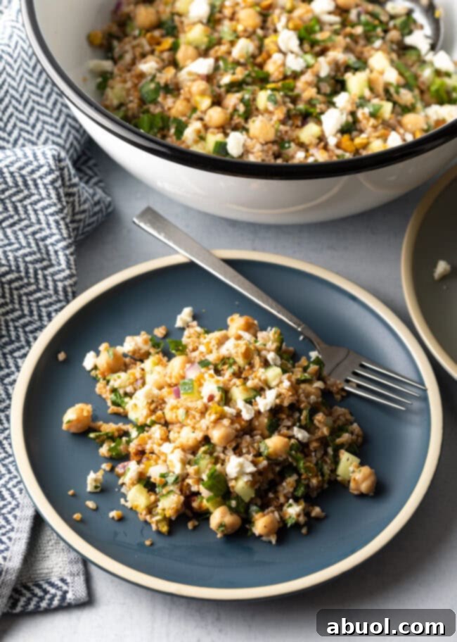 Blue plate with a generous serving of Jennifer Aniston bulgar wheat salad, with a metal fork on the plate.