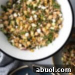 Large white bowl filled with bulgar wheat, veggies, and feta salad.