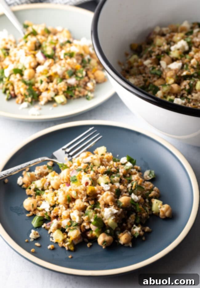 Blue plate with a generous serving of Jennifer Aniston bulgar wheat salad, with a metal fork on the plate.
