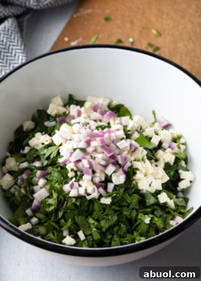 Chopped veggies and bulgar in a large white bowl.