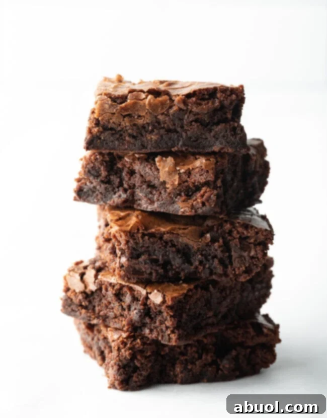 A stack of five perfectly baked, fudgy brownies, showcasing their rich color and inviting texture, placed on a white background, irresistible for any dessert lover.