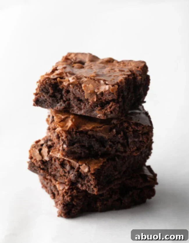 A perfectly arranged stack of four rich, fudgy brownies on a clean white background, highlighting their delicious texture and inviting appearance, ready to be enjoyed.