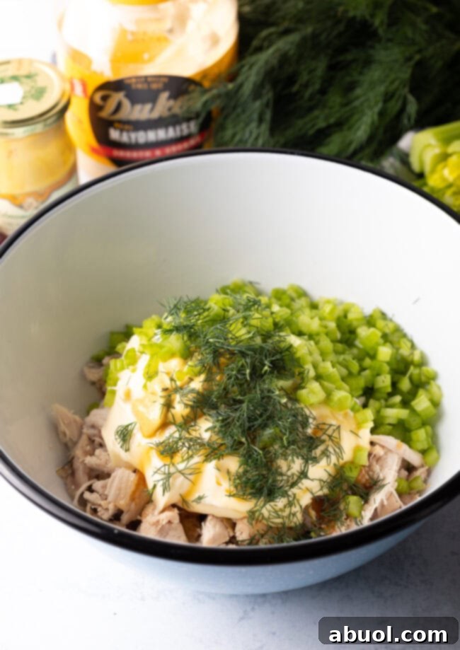 White bowl with shredded poultry, mayo, celery, and fresh dill.