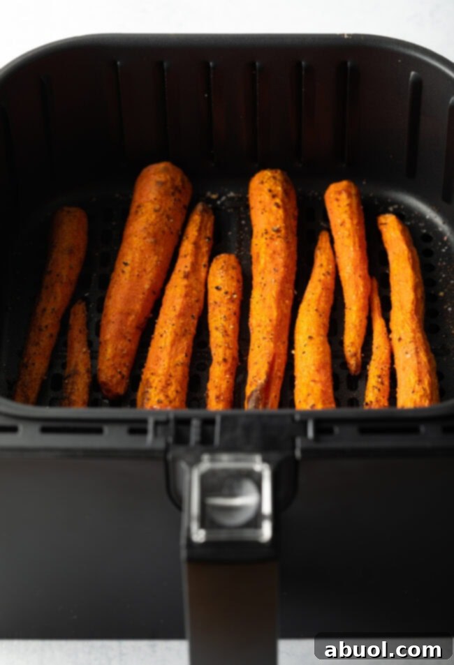 Vertical pile of whole roasted carrots in the fryer basket.