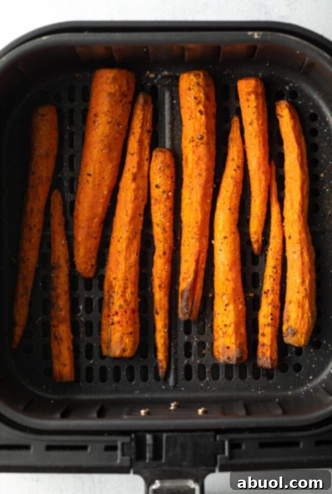 Top down view vertical pile of whole roasted carrots in the fryer basket.