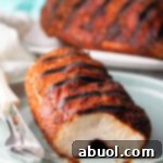 Grilled chicken breast on a plate. The piece is cut to expose the meat inside.