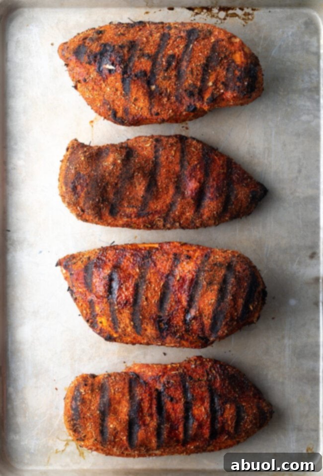 Grilled Blackened Chicken - Four large, expertly grilled chicken breasts, richly seasoned with a blackening spice blend, ready to be served.
