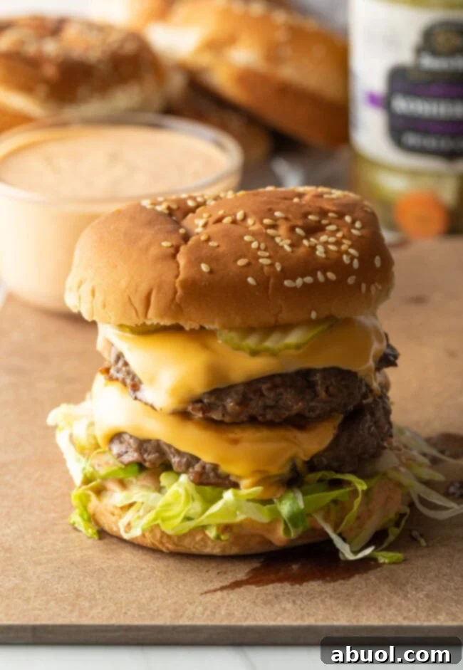 Double patty stacked big Mac burger sitting on a cutting board.