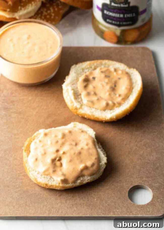 Two halves of hamburger buns, open with a smear of sauce on each.
