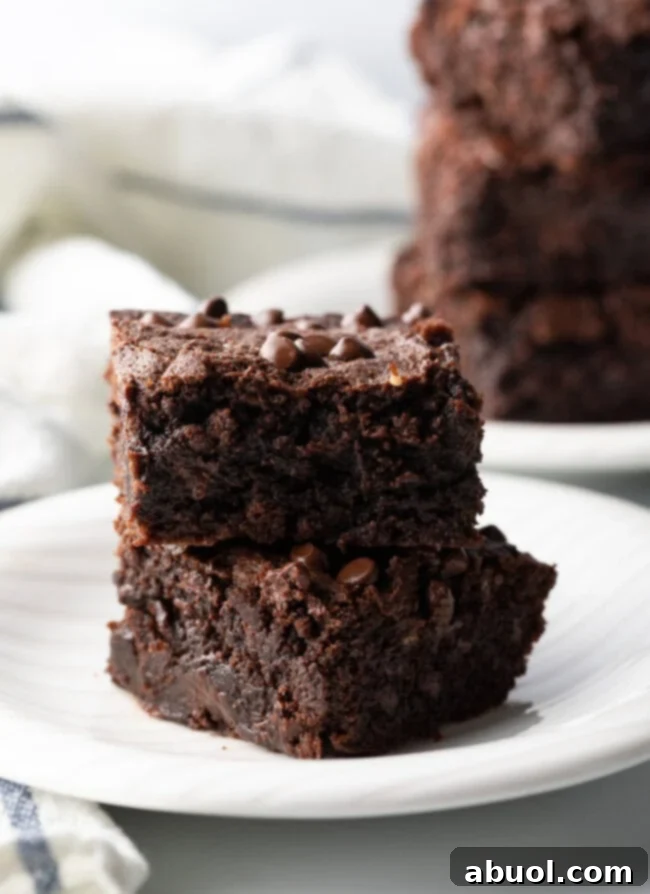 Power & Glow Collagen Brownies 2 Two collagen protein brownies stacked on a white plate, showcasing their fudgy texture.