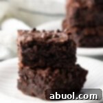 Two collagen protein brownies stacked on a white plate, ready to be enjoyed.