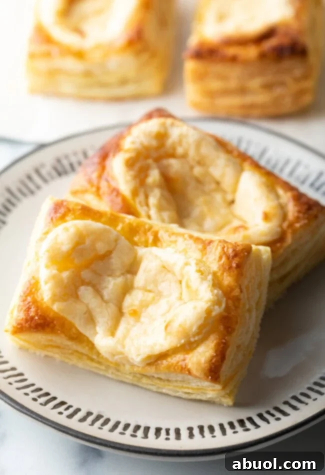 Two large Starbucks style cream cheese danishes on a white plate, showcasing their flaky crust and creamy filling.