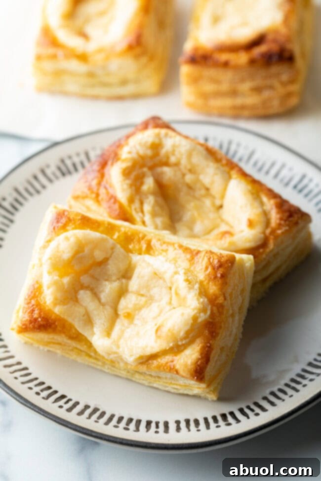 A close-up of two large Starbucks-style cream cheese danishes on a white plate, highlighting their texture.