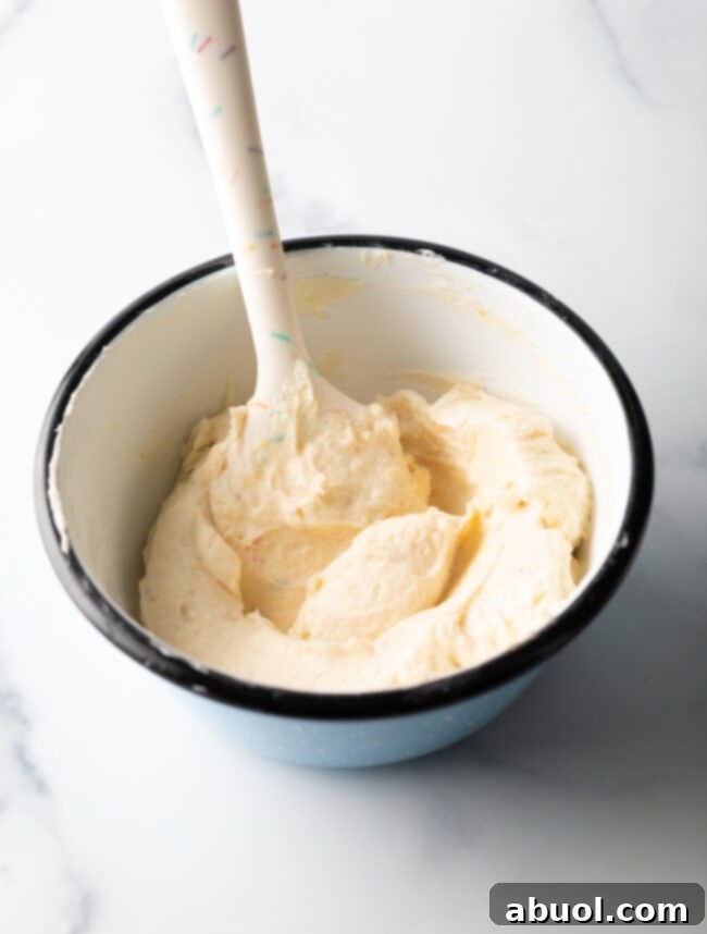 Bowl of softened cream cheese and lemon mixture, perfectly smooth and ready to be piped.