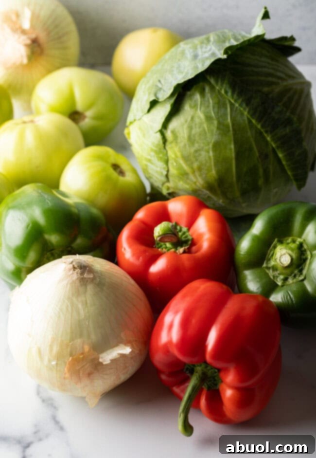 Recipe ingredients: Fresh red bell peppers, green pepper, tomatillos, white onion, and cabbage.