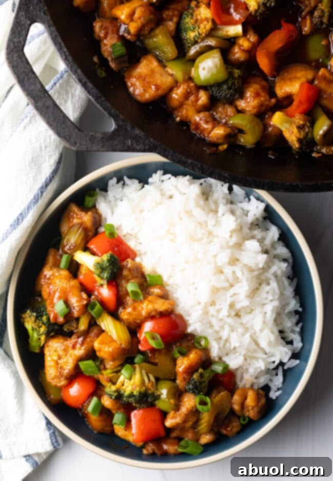 A delicious bowl of Hunan Chicken stir fry with white rice, presented from a top-down view.