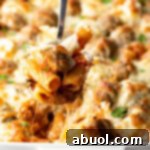 Metal spoon holding a serving of meatball casserole to camera.