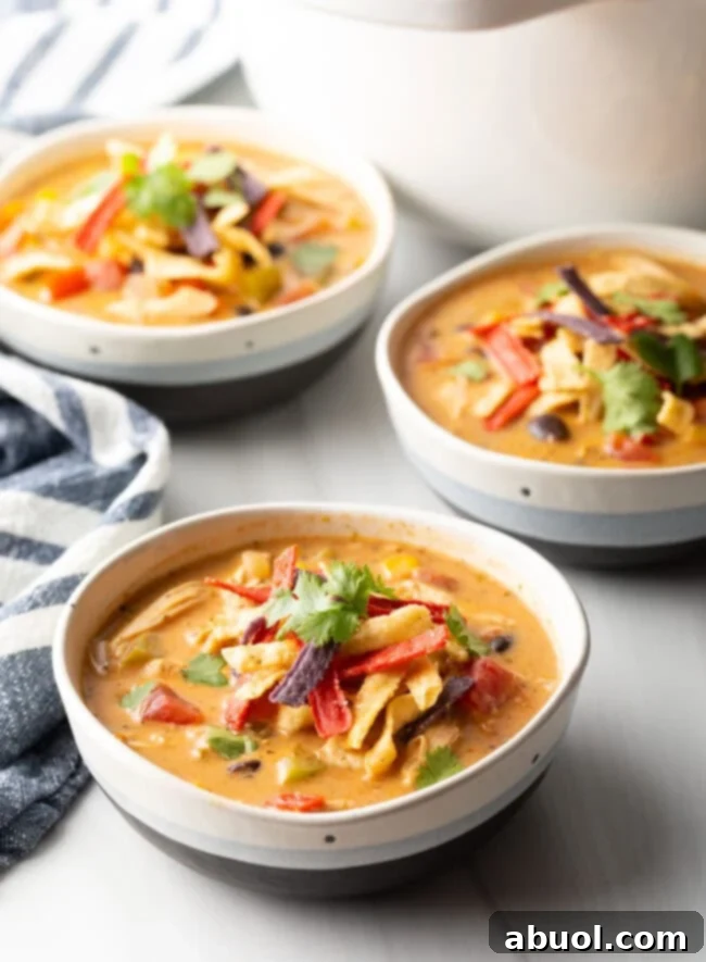 A close-up of a rustic wooden spoon scooping creamy chicken taco soup from a white bowl, garnished with cilantro.