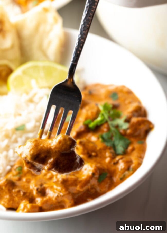 Creamy Lamb Tikka Masala 17 Fork taking a bite of lamb tikka masala curry from a bowl with rice.