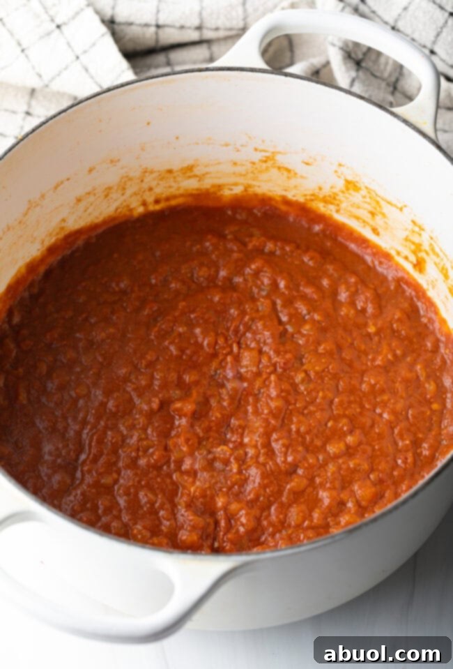 Creamy Lamb Tikka Masala 9 Tomato sauce simmering in a white cooking pot.